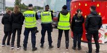 Sju personer står med ryggarna mot kameran, flera har västar med text "polis", "arbetsmiljöverket", "jordbruksverket".